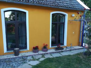 a yellow house with three windows and potted plants at Alte Schäferei in Straupitz
