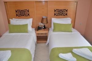 2 camas en una habitación de hotel con almohadas verdes en Hotel Miramar, en Tánger