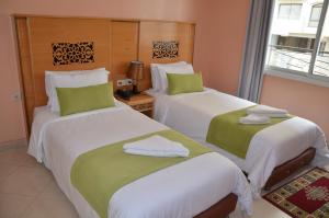 2 letti con lenzuola verdi e bianche in una stanza di Hotel Miramar a Tangeri