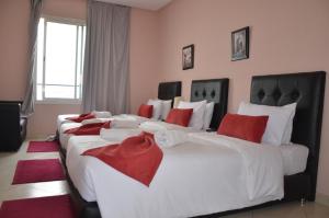 una camera con due grandi letti con cuscini rossi di Hotel Miramar a Tangeri