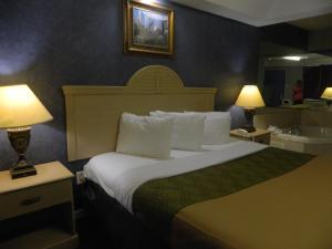 a hotel room with a large bed with two lamps at Village Inn & Suites - Smithville in Smithville