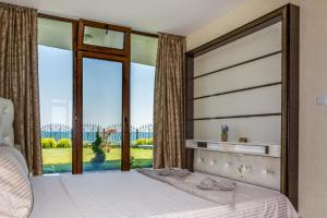 a bedroom with a bed and a large window at Apartcomplex Golden Bay in Ravda