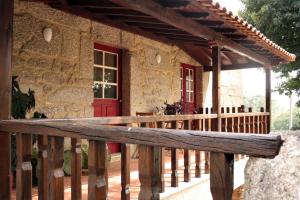 eine Veranda eines Steinhauses mit einer roten Tür in der Unterkunft Casa do Notário in Amares