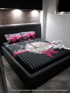 Bett in einem Zimmer mit rosa und schwarzer Bettwäsche in der Unterkunft Micky Santoro -Apartments in Bantayan