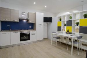 a kitchen with white cabinets and a table with chairs at Ficodì apartments in Alcamo +21 photos