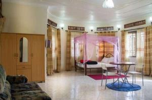 uma sala de estar com uma cama e uma mesa em Palace Hotel em Mbarara