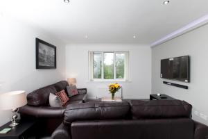 ein Wohnzimmer mit einem braunen Ledersofa und einem TV in der Unterkunft Prime Commuter Executive Apartment Dunfermline in Dunfermline