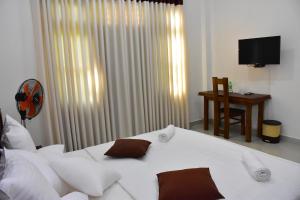 ein Schlafzimmer mit einem weißen Bett mit weißen Kissen in der Unterkunft Ella, Nine Arch Holiday Resort in Ella