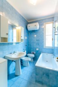 a blue bathroom with a sink and a toilet at Lignano Luxury Villa***** in Lignano Sabbiadoro