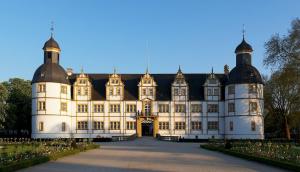 ein großes weißes Gebäude mit schwarzem Dach in der Unterkunft Hotel am Schloss in Paderborn