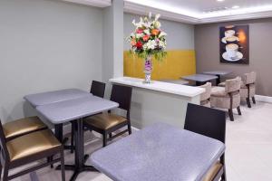 a waiting room with tables and chairs and a vase of flowers at Best Western Plus LA Mid-Town Hotel in Los Angeles