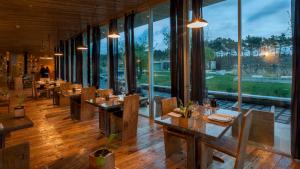 um restaurante com mesas de madeira e janelas grandes em Rio do Prado em Arelho