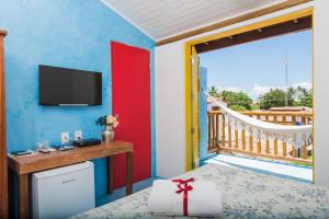 uma sala de estar com uma televisão e uma varanda em Pousada Rosa dos Ventos na Praia do Forte