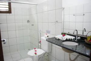 a bathroom with a sink, toilet, and bathtub at Pousada Sol e Luna in Pipa