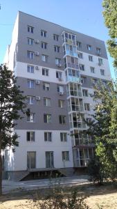 Un edificio alto y blanco con árboles delante. en Morskoi dom, en Odessa