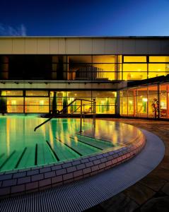 ein großes Gebäude mit einem Swimmingpool bei Nacht in der Unterkunft Baltic Zinnowitz - Hotel mit Meerwasserpool und Thermalbad in Zinnowitz