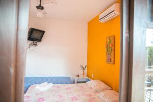 a bedroom with a bed and a tv on the wall at Pousada do Caboclo in Ilhabela