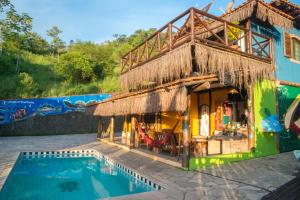 a house with a swimming pool in front of it at Suítes do Caboclo in Ilhabela