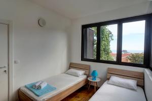 two beds in a room with two windows at Apartments Minja Nerin in Petrovac na Moru