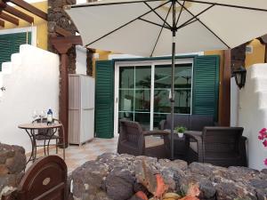 an umbrella on a patio with a table and chairs at Apartamento Rocas del Mar 130 in Costa Del Silencio