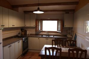 cocina con mesa, sillas y ventana en Can Cabanyes en Llagostera