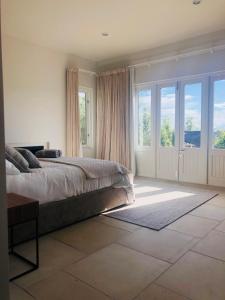 a bedroom with a large bed and large windows at Cable Bay Villa in Oneroa