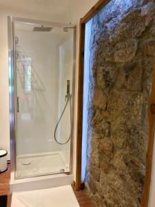 y baño con ducha y pared de piedra. en Apartamenty Sudeckie nad zalewem, en Sosnówka 33 fotos más