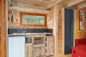 a kitchen in a log cabin with a sink and a window at Cabane des Guernazelles in Valderoure