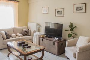 uma sala de estar com um sofá e uma televisão em Artemis central apartment em Kórinthos