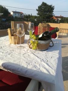 a table with wine glasses and a basket of grapes at Apartman Nada in Kornić
