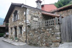 un antico edificio in pietra con una recinzione in legno di Casa Rural La Xiarapina a Serrapio