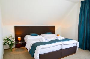 a bedroom with a bed with white sheets and blue pillows at PENZION POD ZÁMKEM in Valtice