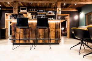 a bar with two stools in a room with reclaimed wood at Peakini Farmhaus in Untertauern