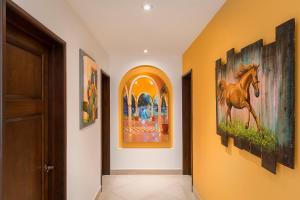 a hallway with paintings of a horse on the wall at The Residences at Hacienda Encantada in Cabo San Lucas