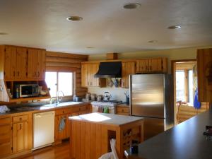 una cucina con armadi in legno e frigorifero in acciaio inossidabile di Fish Creek House Bed & Breakfast a Silver Star