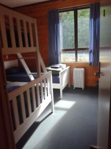 1 dormitorio con 2 literas y ventana en JunoHall Backpackers, en Waitomo Caves