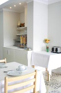 a white kitchen with a white table and chairs at Hotel Lagoa dos Pastorinhos in Fátima