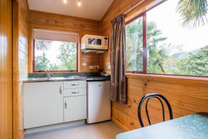 a kitchen with white appliances and a large window at Nelson City TOP 10 Holiday Park in Nelson
