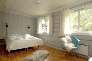 a bedroom with a bed and a chair and a window at Elveseter Hotell in Boverdalen