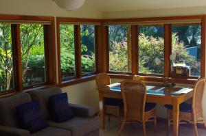a dining room with a table and chairs and windows at Joya Garden & Villa Studios in Nelson