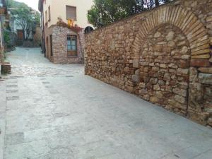 an alley with a stone wall next to a street at Can Misse in Collbató