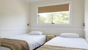 two beds in a room with a window at NRMA Stockton Beach Holiday Park in Stockton