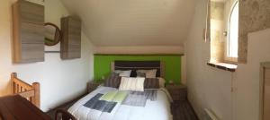 Dormitorio pequeño con cama con pared verde en Gîte Le Cézan, en Jégun