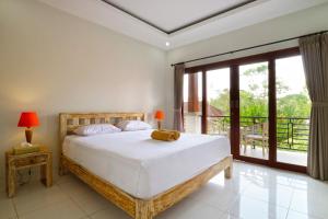 a bedroom with a large bed and a balcony at Avisara Villa & Suite in Nusa Dua