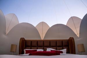 a bedroom with a bed with white walls and red pillows at Petra Bubble Luxotel in Wadi Musa