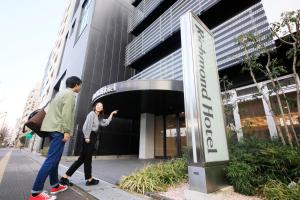 Richmond Hotel Higashi Osaka في أوساكا: رجل وامرأة يقفان أمام مبنى
