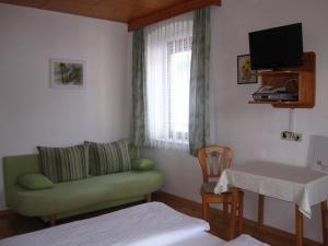 ein Wohnzimmer mit einem grünen Sofa und einem Tisch in der Unterkunft Gasthof Ebner in Absam