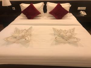 two white flowers on a white bed with red pillows at Apple Hotel Two - Near Phnom Penh Airport in Phnom Penh