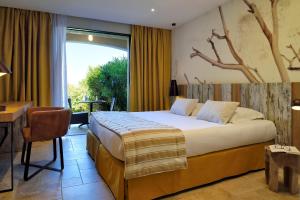 a bedroom with a bed and a desk and a window at Hotel Bartaccia in Propriano