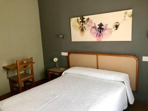 a bedroom with a bed and a chair and a picture of flowers at Hostal Puerta La Villa in Tordesillas